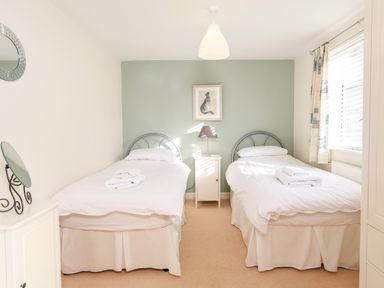 A bedroom with two single beds and a nightstand with a lamp between the beds at 2 The Bay in Bigbury