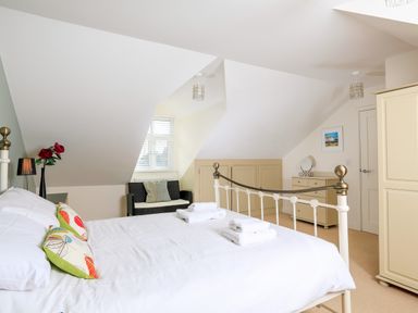 A bedroom with a bed a wardrobe a chest of drawers and a small sofa at 2 The Bay in Bigbury