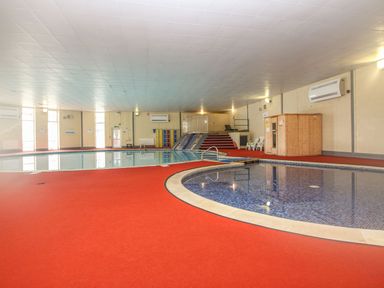 An indoor swimming pool area with a small pool and a larger pool alongside a wooden cabin on the side at 59 Valley Lodge in Callington near Gunnislake