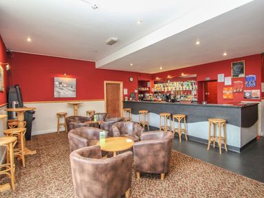 A bar with seating including stools and armchairs around tables at 59 Valley Lodge Callington near Gunnislake