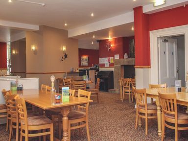 A dining area with wooden tables and chairs and a fireplace at 59 Valley Lodge in Callington near Gunnislake