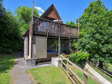 A two story house with a balcony and a wooden fence surrounded by trees at 59 Valley Lodge in Callington near Gunnislake