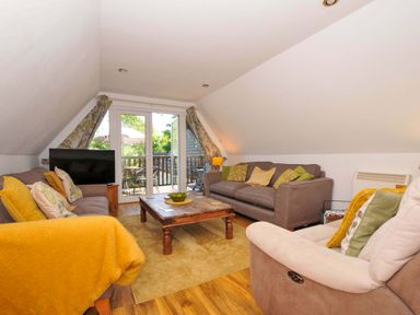 A living room with sofas a wooden coffee table and a TV near glass doors opening to a balcony at 59 Valley Lodge Callington near Gunnislake
