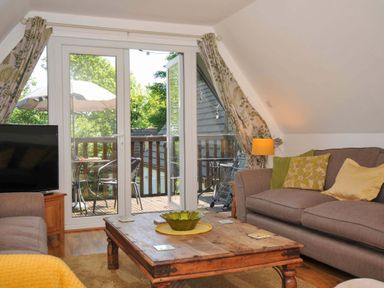 A living room with sofas pillows a wooden coffee table and glass doors opening to a balcony at 59 Valley Lodge Callington near Gunnislake