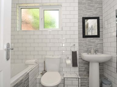 A bathroom with a toilet sink and bathtub with tiled walls at 59 Valley Lodge in Callington near Gunnislake
