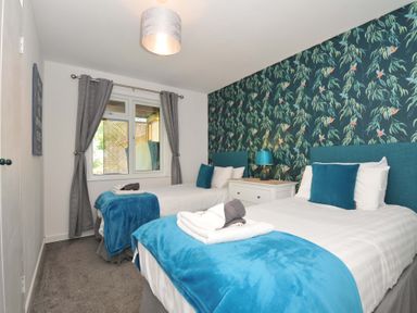 A bedroom with two single beds blue throws and floral wallpaper at 59 Valley Lodge in Callington near Gunnislake