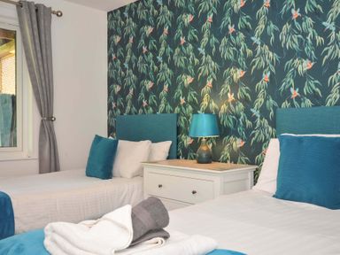 A bedroom with two single beds a white nightstand and a lamp at 59 Valley Lodge Callington near Gunnislake