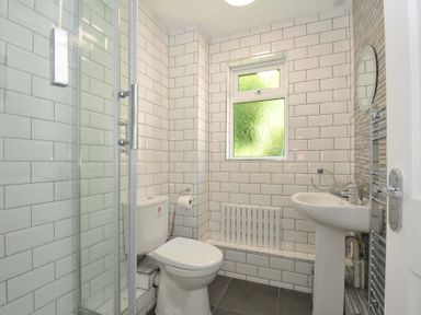 A bathroom with a shower cubicle toilet pedestal sink and a frosted window at 59 Valley Lodge in Callington near Gunnislake