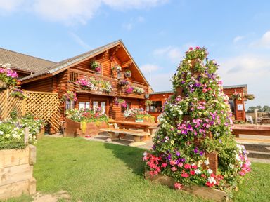A wooden house with numerous flower arrangements and benches outside at Jalan End in Felton