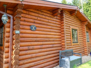 An exterior view of a log cabin with a bench and two windows at Jalan End in Felton