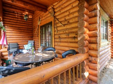 A wooden porch with a glass table and chairs and wine glasses at Jalan End in Felton