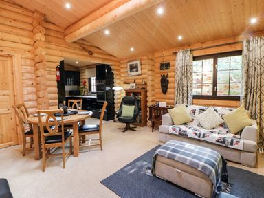A wooden interior living room with a dining table set sofa and armchair at Jalan End in Felton