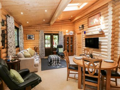 A living and dining area with wooden furniture and log walls at Jalan End in Felton