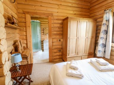 A bedroom with a wooden wardrobe bed with towels and a side table with a blue lamp at Jalan End in Felton