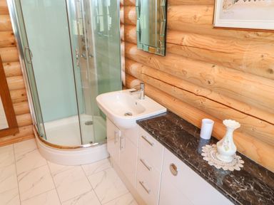 A bathroom with a glass shower enclosure and a white sink with cabinets at Jalan End in Felton