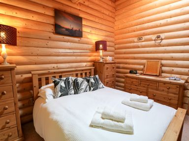 A bedroom with a wooden bed white bedding patterned pillows wooden dressers and two lamps at Jalan End in Felton