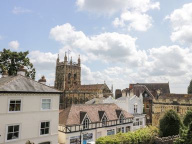 Buildings with a church tower in the background under a cloudy sky at The Hideaway in Malvern