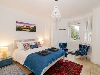 A bedroom with a double bed lamps two chairs and a door leading outside at The Hideaway in Malvern