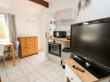 A kitchen area with a wooden chest of drawers microwave oven and television at The Nook in Star near Cenarth