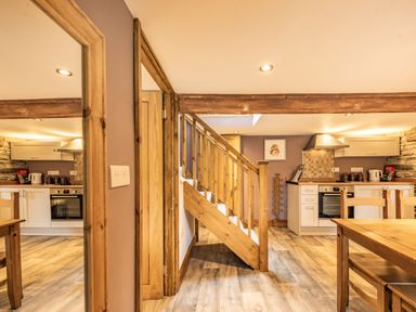 A kitchen and dining area with wooden stairs and furniture at Pendre Cottage in Cenarth