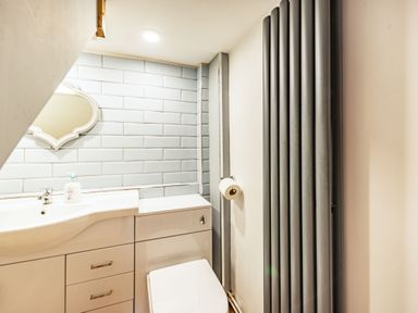 A bathroom with a sink, cabinet, toilet, wall mirror, hand soap, tiled wall and vertical radiator at Pendre Cottage in Cenarth