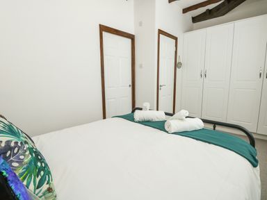 A bedroom with a bed holding rolled towels and pillows with cupboards and two doors at The Brewery in Brewers Quay Harbour