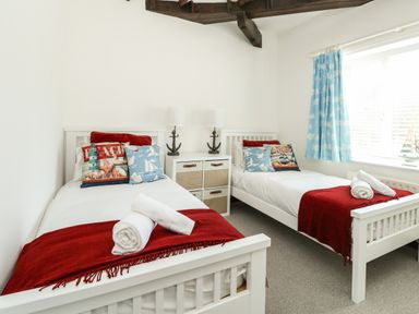 A bedroom with two white single beds with red blankets and nautical themed pillows at The Brewery in Brewers Quay Harbour
