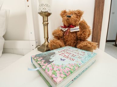 A bedside table with a teddy bear a lamp and a book titled illustrated fairy tales at The Brewery in Brewers Quay Harbour