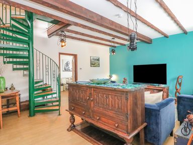A living room with a green spiral staircase wooden cabinet and a blue wall at The Brewery in Brewers Quay Harbour