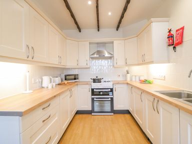 A kitchen with white cabinets wooden countertops stove microwave kettle and sink at The Brewery Brewers Quay Harbour