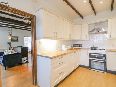 A kitchen with white cabinets wooden countertops a stove and microwave with a view into a living room at The Brewery Brewers Quay Harbour