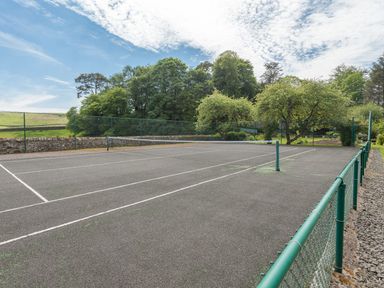 An outdoor tennis court with fencing and trees in the background at Greystead Institute in Bellingham