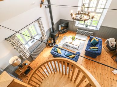 A living room with blue sofas pillows a wood stove a coffee table and a spiral staircase at Greystead Institute in Bellingham
