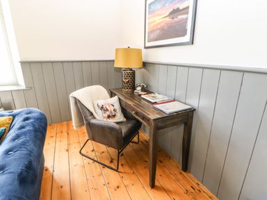 A corner with a wooden desk and chair on a wooden floor next to a blue sofa at Greystead Institute in Bellingham