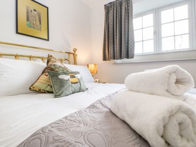 A bedroom with a brass bed frame two decorative pillows and rolled white towels on a quilted blanket at Greystead Institute in Bellingham