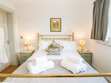 A bedroom with a brass bed frame bedside tables with lamps and folded towels on the bed at Greystead Institute in Bellingham