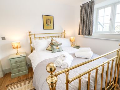 A bedroom with a brass bed and folded towels on a quilt at Greystead Institute in Bellingham