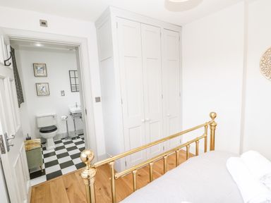 A bedroom with a brass bed frame white wardrobe wooden floor and an adjacent bathroom with checkered floor at Greystead Institute in Bellingham