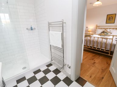 A bathroom with a walk-in shower and towel rack next to a bedroom with a brass bed frame at Greystead Institute in Bellingham