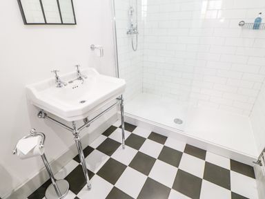 A bathroom with a white sink and chrome fixtures a toilet paper holder and a glass shower at Greystead Institute in Bellingham