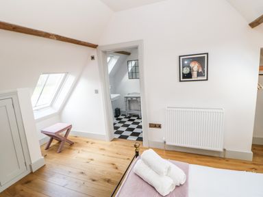 A bedroom with wooden floor a window seat and an open door leading to a bathroom with a black and white tiled floor at Greystead Institute in Bellingham