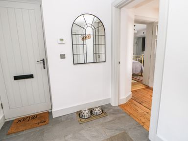 An entryway with a gray door a mat two pet bowls on the floor a mirror on the wall and a view into a bedroom at Greystead Institute in Bellingham