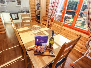 A dining table with a bottle, eggs, chocolates, coffee pods, and tea bags in a kitchen at Rowan Lodge in Greetham Rutland