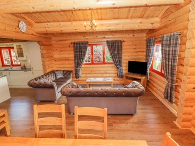 A living room with two sofas a wooden coffee table a television and plaid curtains at Maple Lodge in Greetham Rutland