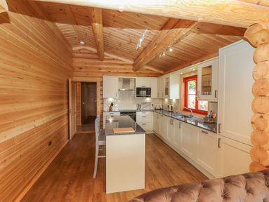 A kitchen with white cabinets wooden walls and ceiling and a kitchen island at Maple Lodge in Greetham Rutland