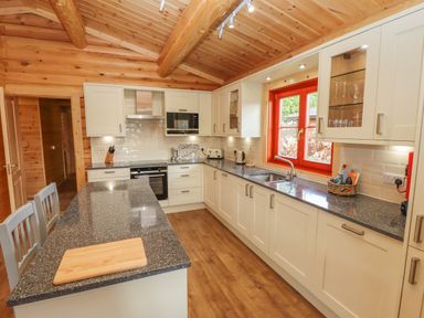 A kitchen with white cabinets black countertops and a window with red frame at Maple Lodge in Greetham Rutland