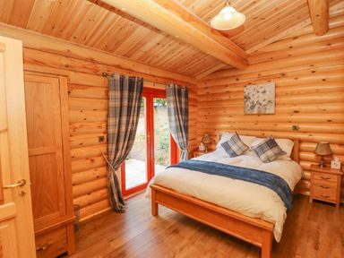 A bedroom with a wooden bed and plaid curtains at Maple Lodge in Greetham Rutland