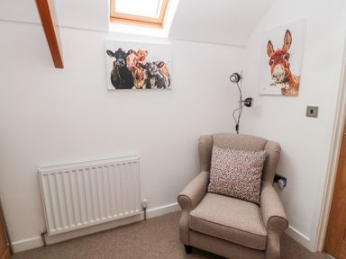 A corner of a room with an armchair and animal paintings on the wall at Grange Cottages in Alnwick