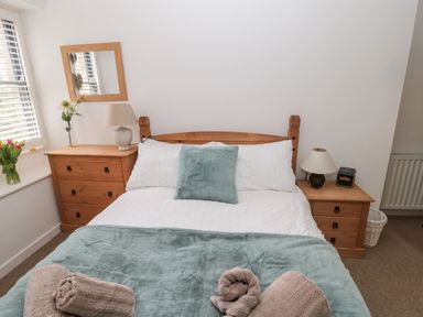 A bedroom with a wooden bed and two wooden bedside tables with lamps at Grange Cottages in Alnwick
