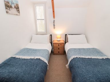 A bedroom with two single beds blue blankets a wooden bedside table and a lamp at Grange Cottages in Alnwick